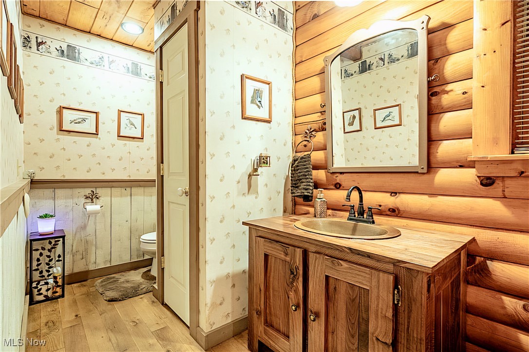 49144 Hickman Road Calcutta, OH 43920 - Photo 17 of 23 Bathroom with vanity, hardwood / wood-style flooring, wooden ceiling, log walls, and toilet