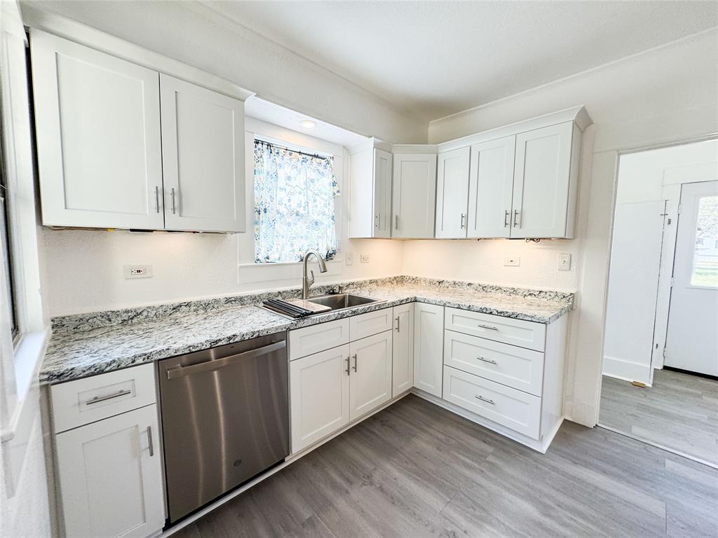 904 West 7th Street Cisco, TX 76437 - Photo 13 of 37 a kitchen with granite countertop white cabinets and white appliances with wooden floor