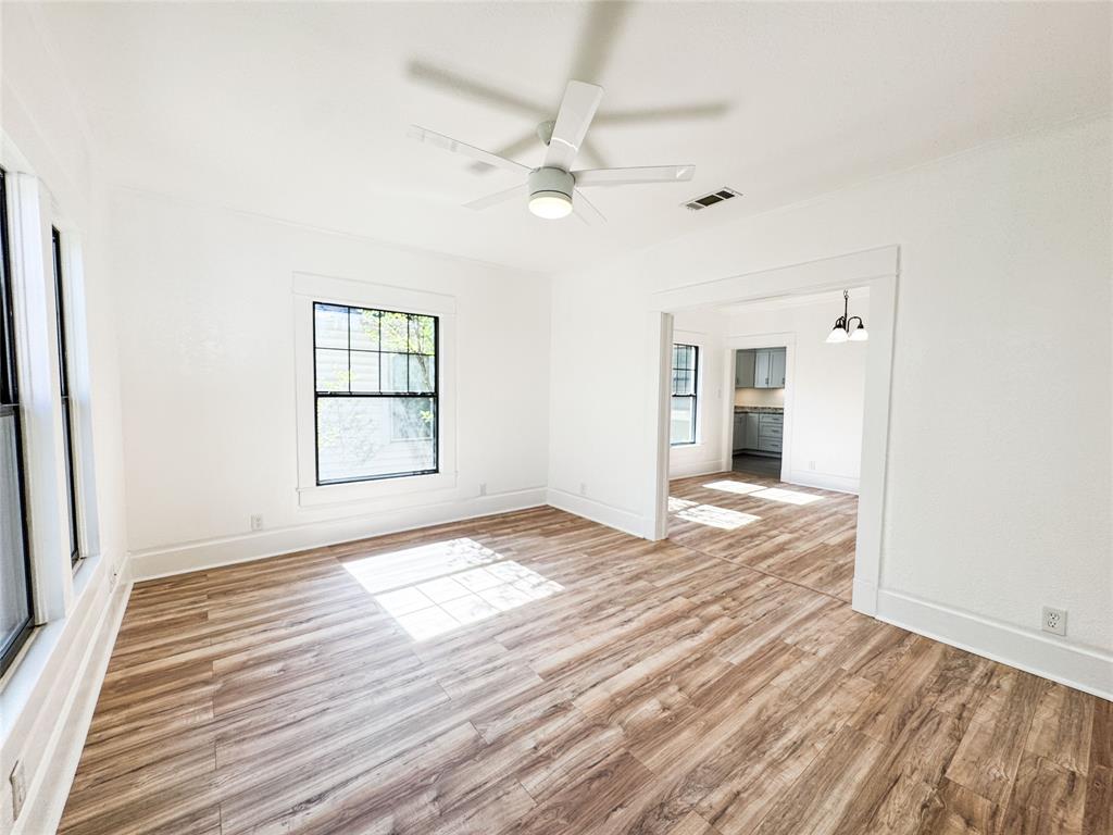 904 West 7th Street Cisco, TX 76437 - Photo 8 of 37 an empty room with wooden floor chandelier fan and windows