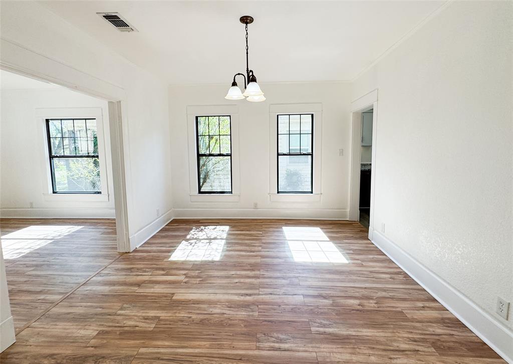 904 West 7th Street Cisco, TX 76437 - Photo 10 of 37 an empty room with wooden floor chandelier and windows