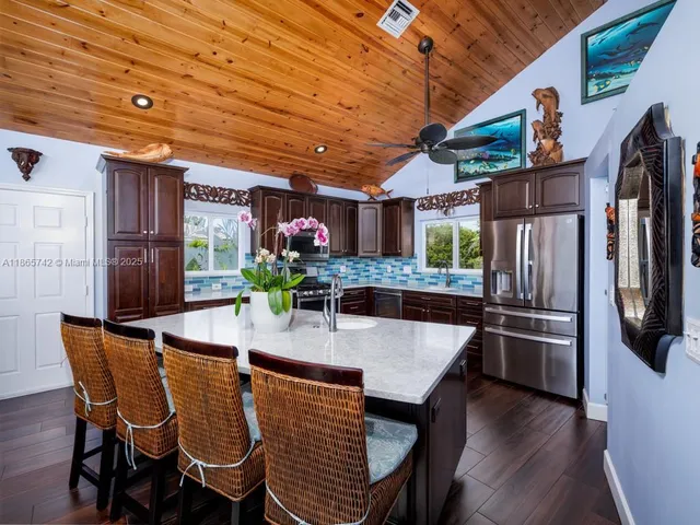 a kitchen with stainless steel appliances granite countertop a refrigerator a stove and a sink with wooden floor