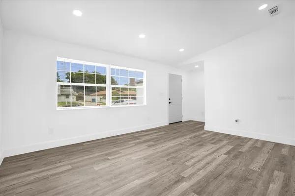 an empty room with wooden floor and windows