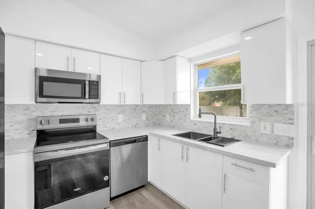 a kitchen with stainless steel appliances granite countertop a sink a stove a microwave and wooden cabinets