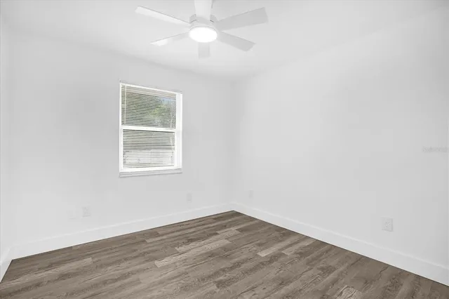 an empty room with wooden floor fan and window