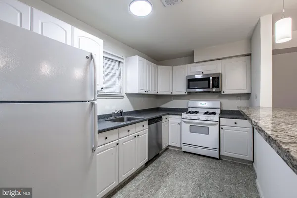 a kitchen with stainless steel appliances granite countertop a refrigerator a stove top oven a sink and dishwasher