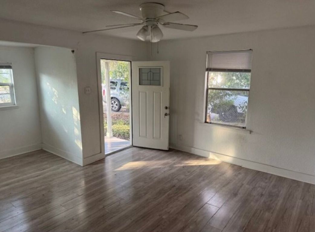 3207 Burleson Road, Unit 1 Austin, TX 78741 - Photo 3 of 11 an empty room with wooden floor chandelier fan and windows
