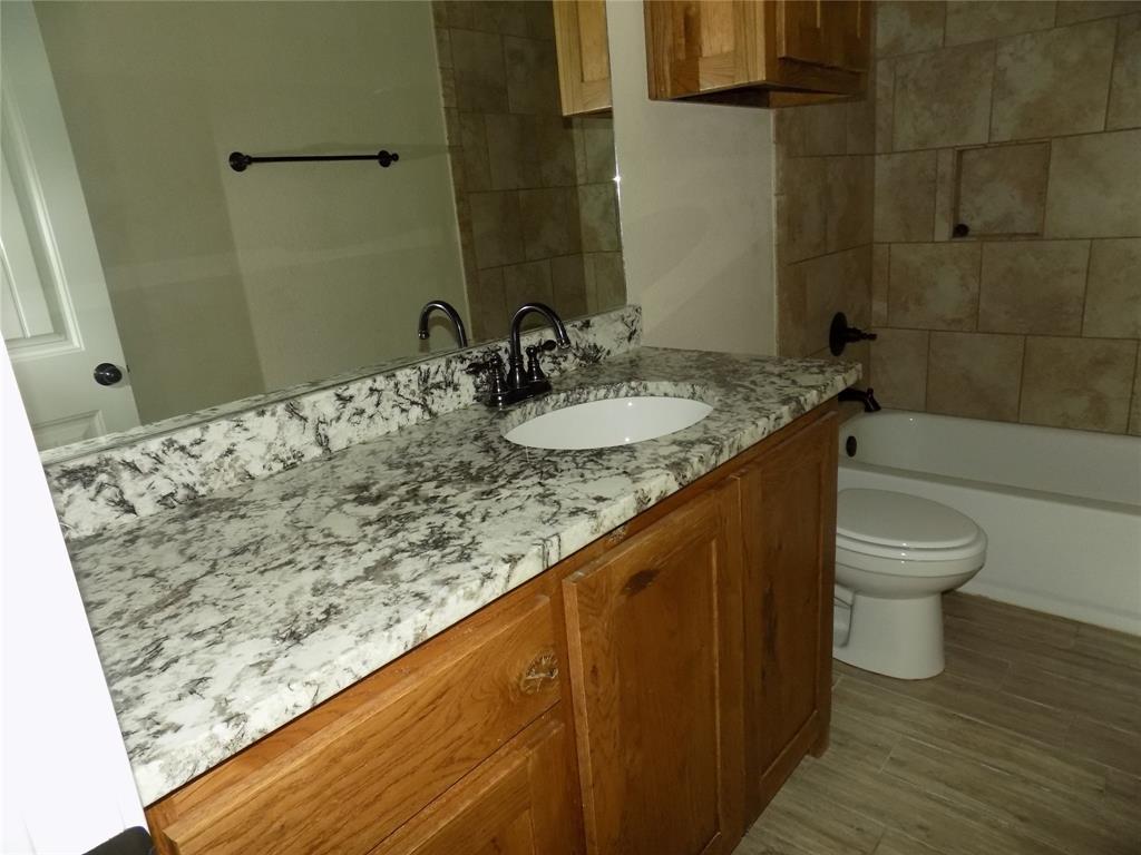 2007 Brown Loop Poolville, TX 76487 - Photo 21 of 32 a bathroom with a granite countertop sink and a toilet