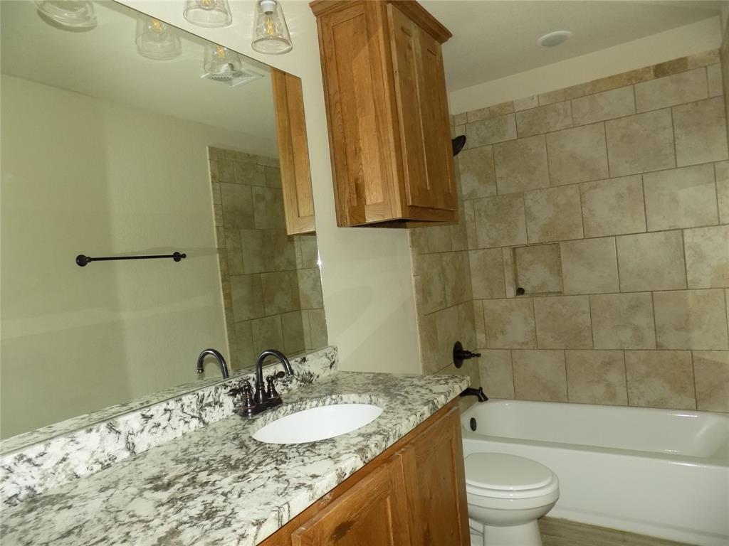 2007 Brown Loop Poolville, TX 76487 - Photo 22 of 32 a bathroom with a granite countertop sink a mirror and a bathtub
