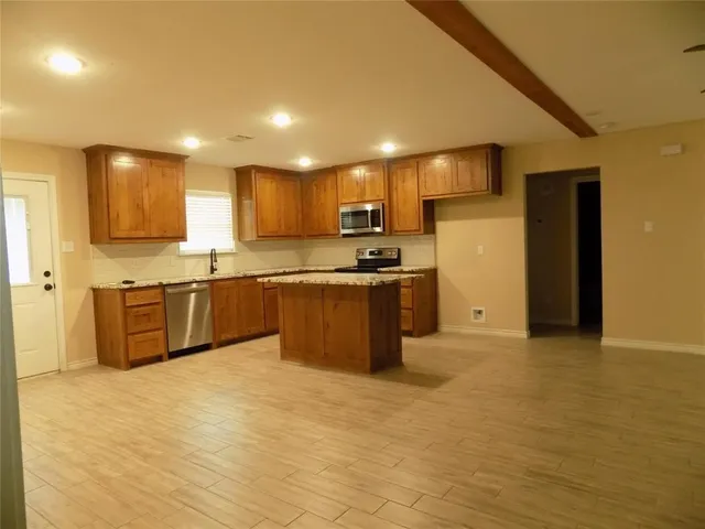 a kitchen with stainless steel appliances granite countertop a sink a stove top oven a counter space and cabinets