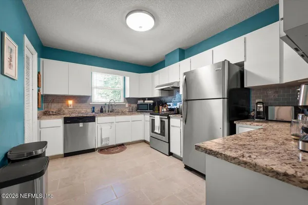 a kitchen with a refrigerator a stove top oven a sink and cabinets