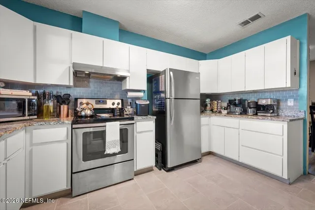 a kitchen with refrigerator a stove a sink and cabinets