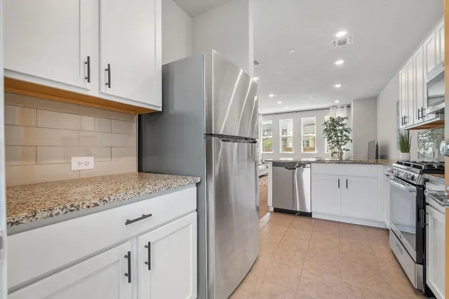 a kitchen with white cabinets and stainless steel appliances