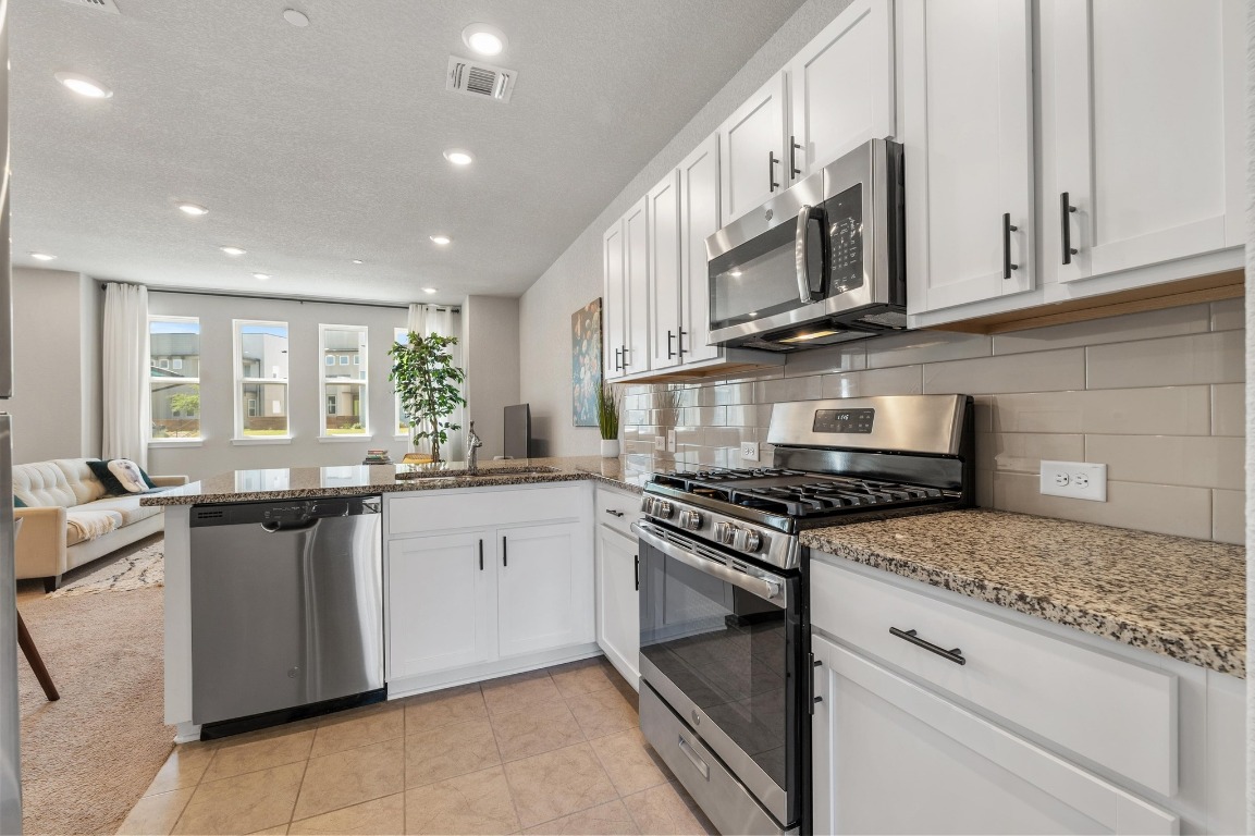 9015 Cattle Baron Path, Unit 403 Austin, TX 78747 - Photo 12 of 40 a kitchen with stainless steel appliances granite countertop a stove and a microwave