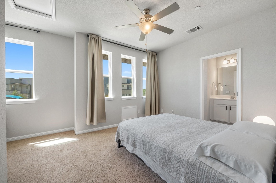 9015 Cattle Baron Path, Unit 403 Austin, TX 78747 - Photo 15 of 40 a bedroom with a large bed and a chandelier