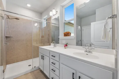 a bathroom with a double vanity sink a mirror and a shower