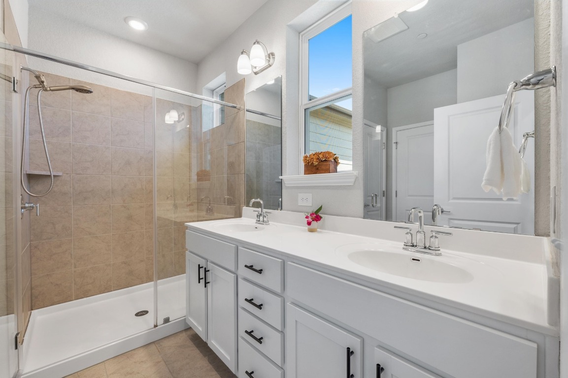 9015 Cattle Baron Path, Unit 403 Austin, TX 78747 - Photo 23 of 40 a bathroom with a double vanity sink a mirror and a shower