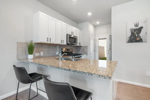 a kitchen with stainless steel appliances granite countertop a sink a stove a microwave a refrigerator and cabinets