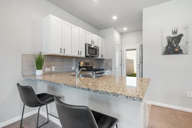 a kitchen with stainless steel appliances granite countertop a sink a stove a microwave a refrigerator and cabinets