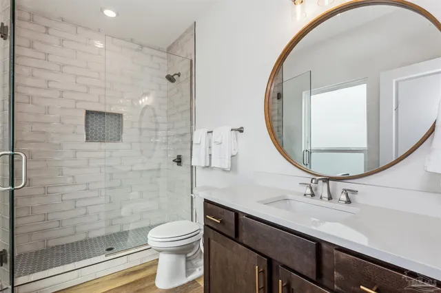 a bathroom with a toilet sink vanity shower and mirror