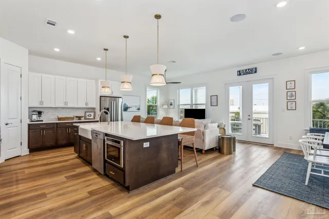 a large kitchen with stainless steel appliances kitchen island granite countertop a large counter top a sink and a wooden floors