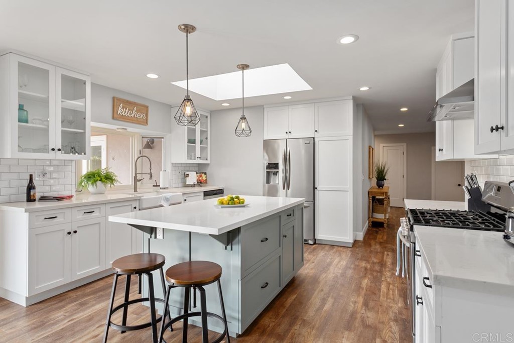 a kitchen with a sink a refrigerator a stove and white cabinets with wooden floor