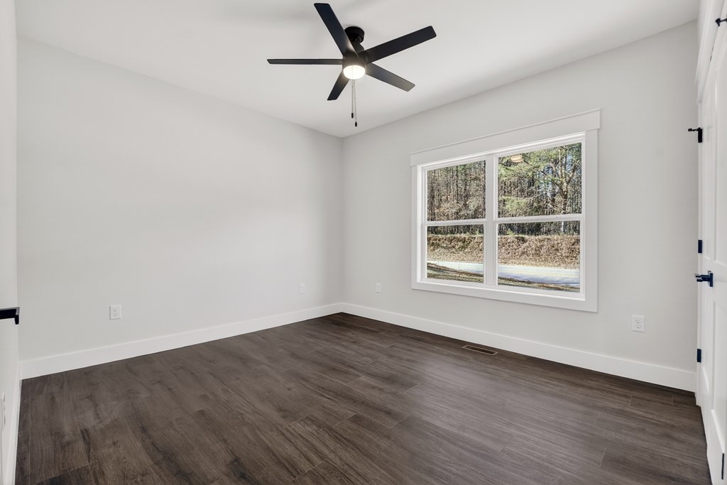 584 Brannon Nix Road Young Harris, GA 30582 - Photo 23 of 36 an empty room with wooden floor ceiling fan and windows