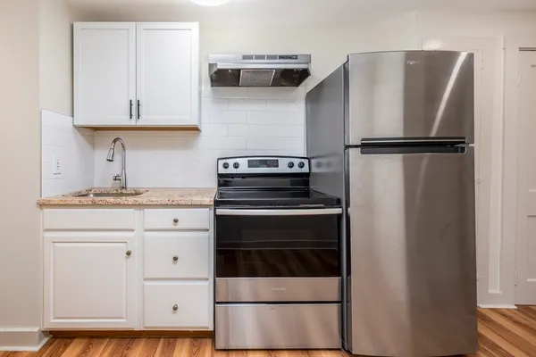 a kitchen with granite countertop white cabinets and stainless steel appliances