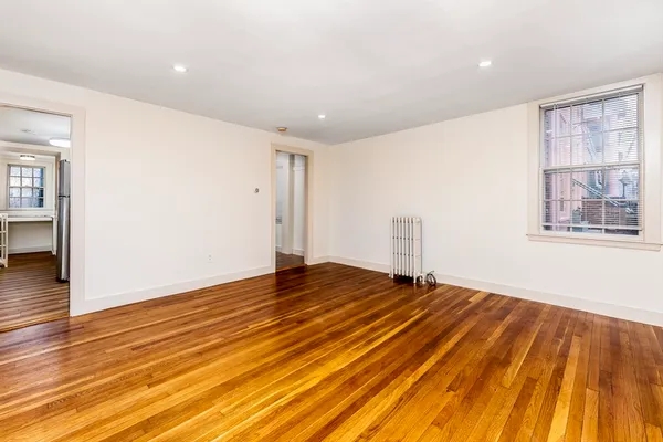 a view of an empty room with wooden floor and a window