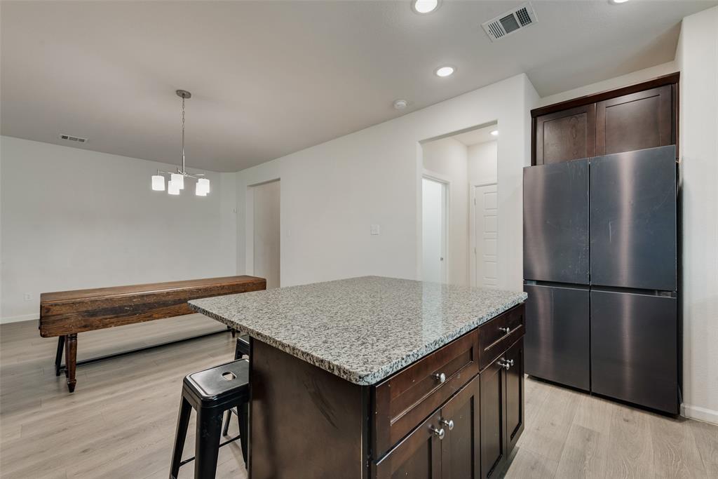 624 Hazeltine Road Red Oak, TX 75154 - Photo 15 of 37 a kitchen with kitchen island a wooden floor and refrigerator