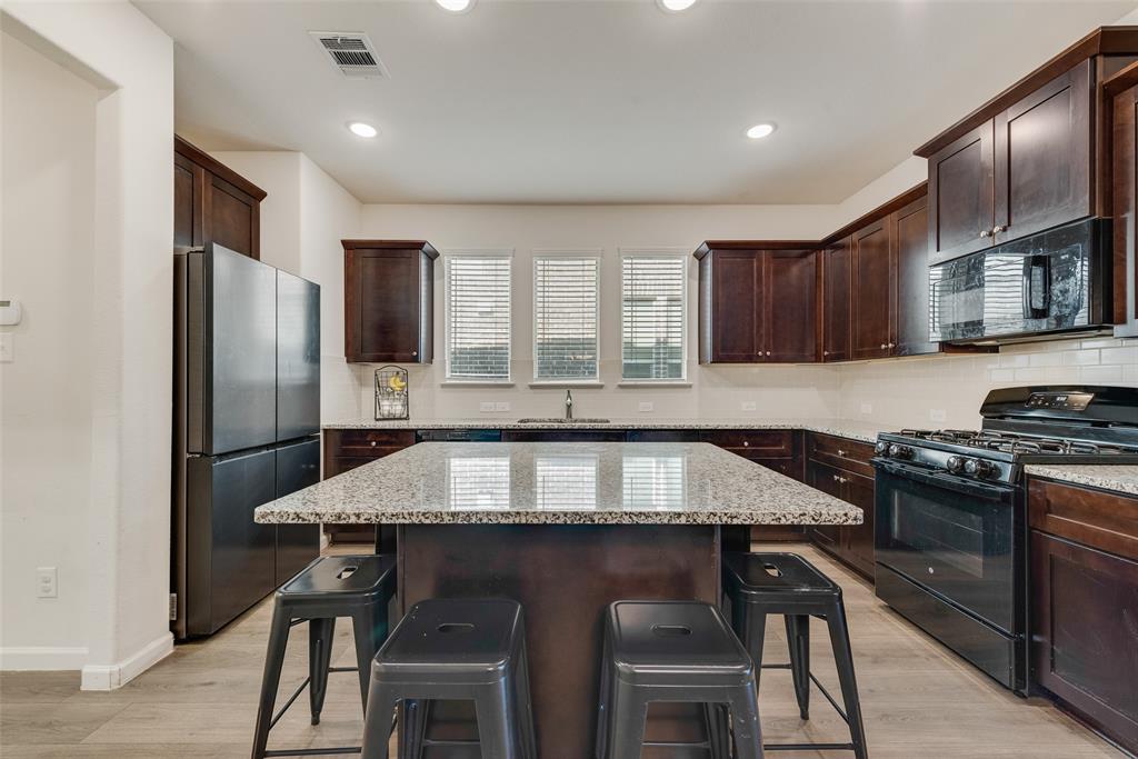 624 Hazeltine Road Red Oak, TX 75154 - Photo 17 of 37 a kitchen with stainless steel appliances granite countertop a stove a refrigerator a sink a stove a dining table and chairs