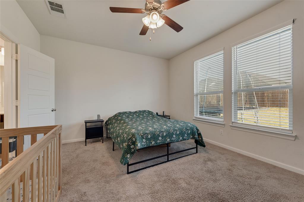 624 Hazeltine Road Red Oak, TX 75154 - Photo 21 of 37 a bedroom with a bed and a chandelier