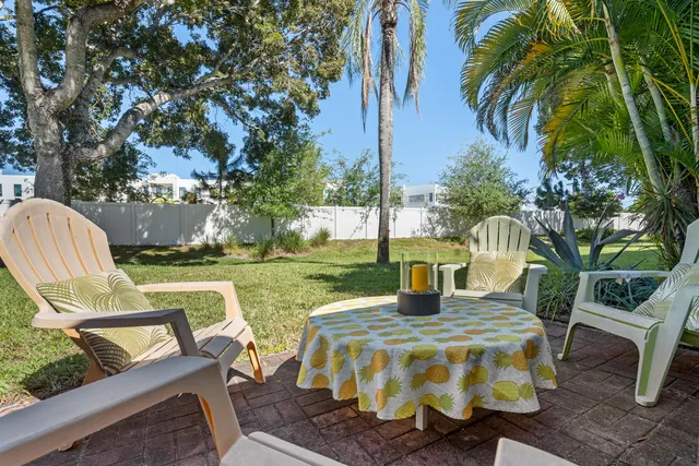 a view of a patio with table and chairs potted plants and palm tree