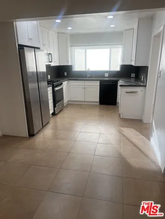 a kitchen with granite countertop stainless steel appliances a sink a counter top space and a window