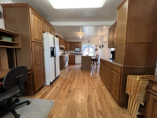 a kitchen with stainless steel appliances granite countertop a refrigerator a stove a sink dishwasher and wooden cabinets with wooden floor