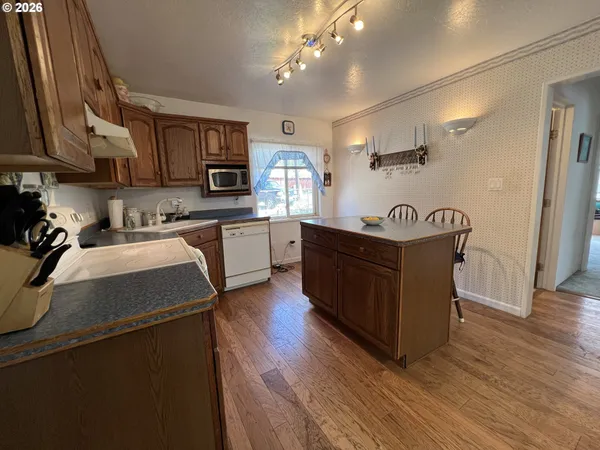 a kitchen with stainless steel appliances granite countertop a sink a stove and a wooden floors