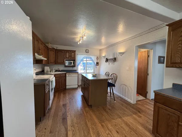 a kitchen with kitchen island granite countertop wooden floors stainless steel appliances and dining table