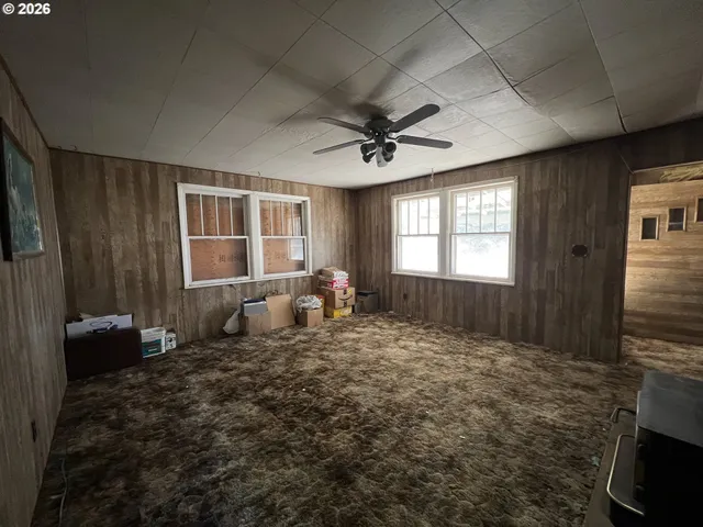 a view of a livingroom with a fireplace a ceiling fan and windows