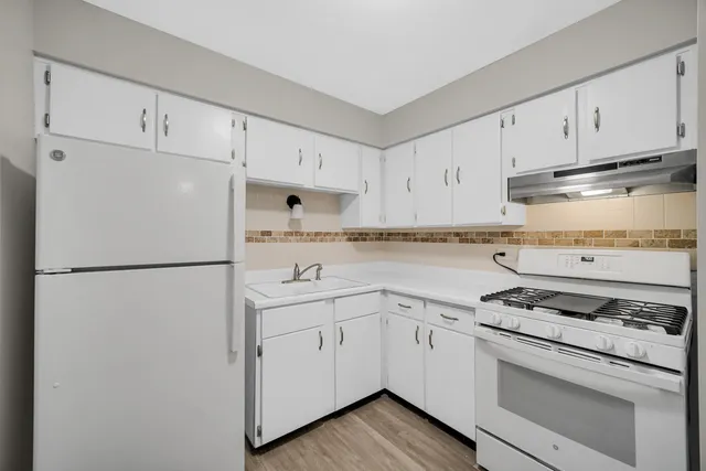 a white refrigerator freezer sitting inside of a kitchen with white cabinets