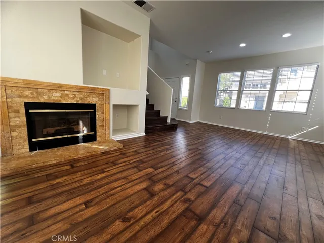 an empty room with wooden floor fireplace and windows