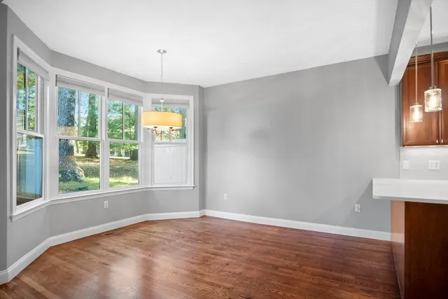 a view of an empty room with window and wooden floor