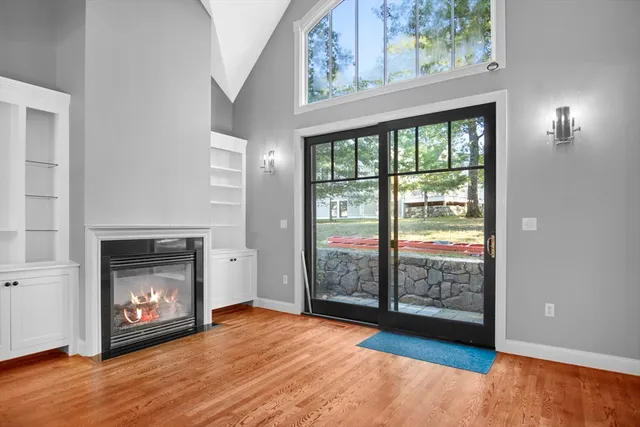 a view of an empty room with wooden floor fireplace and a window