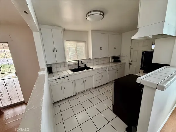 a kitchen with a sink dishwasher stove and white cabinets