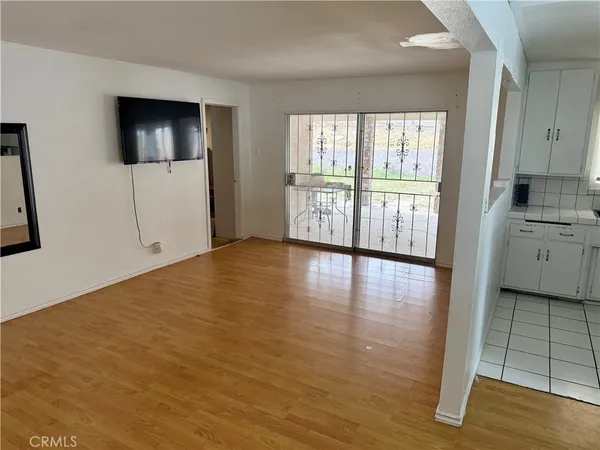 a view of a livingroom with wooden floor and a kitchen