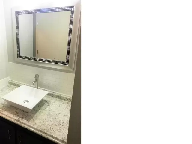 a bathroom with a granite countertop sink and a mirror