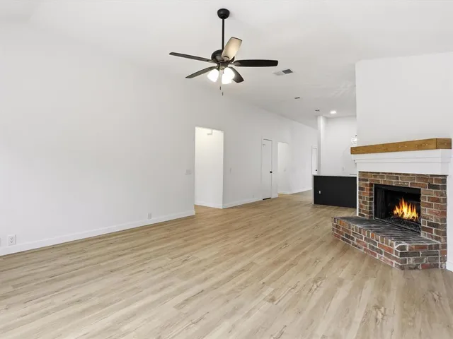 a view of a livingroom with a fireplace a ceiling fan and kitchen floor