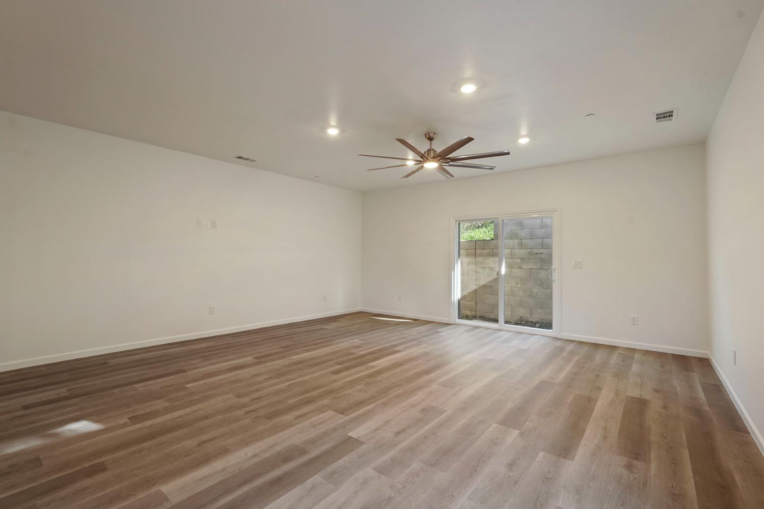 3286 Botfuher Road Valley Springs, CA 95252 - Photo 4 of 24 a view of an empty room with wooden floor and a ceiling fan