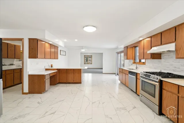 a large kitchen with stainless steel appliances granite countertop a stove and a sink