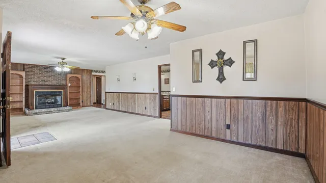 an empty room with windows fireplace and fans