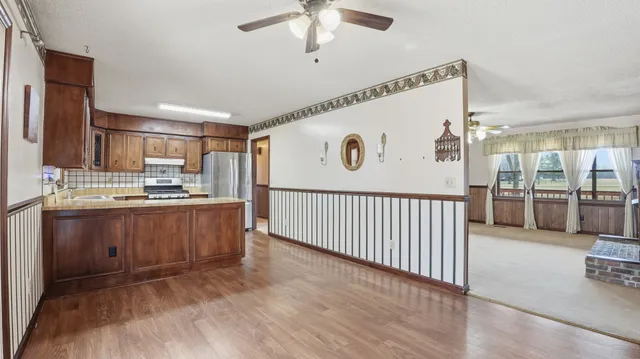 an empty room with chandelier fan and windows