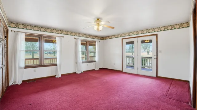 an empty room with chandelier fan and windows